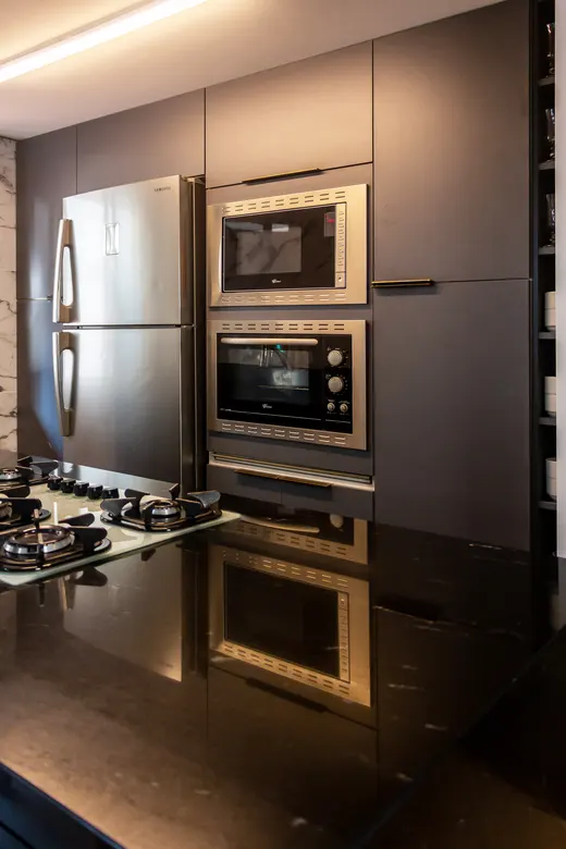 Cozinha planejada em grafite, com torre de forno e micro-ondas embutidos e bancada preta