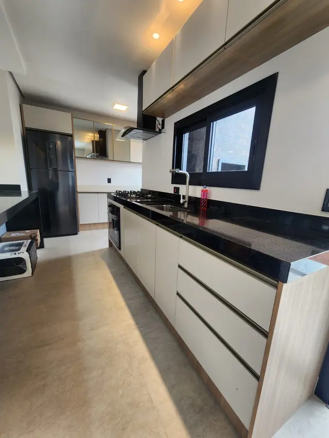Cozinha planejada em corredor, com armários off-white, bancada preta e acabamento em madeira
